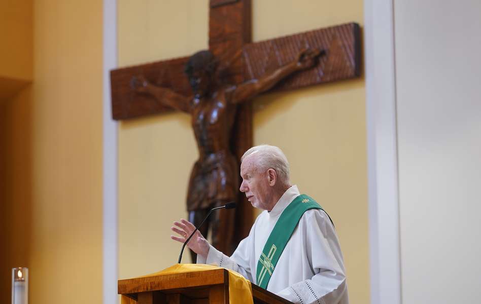 Priest speaking at a church lectern with a crucifix behind him