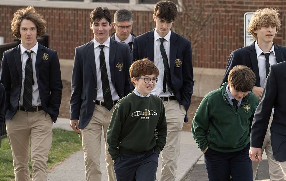 A group of schoolboys in uniforms walking outside a brick school building